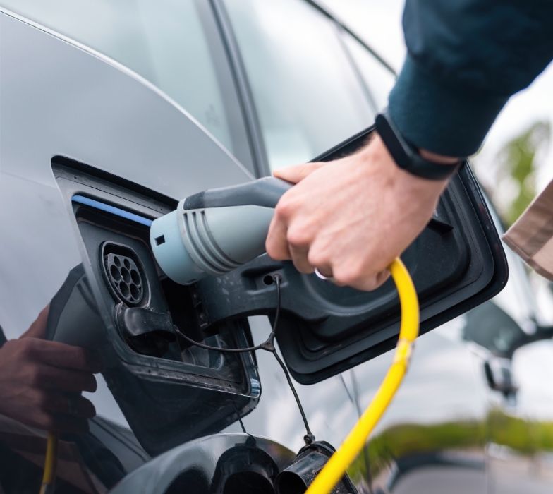 person plugging in an electric vehicle (EV) to a EV charging point